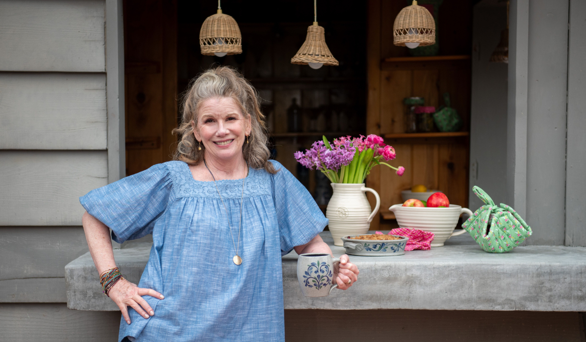 Melissa Gilbert holding a mug. Flowers behind her.