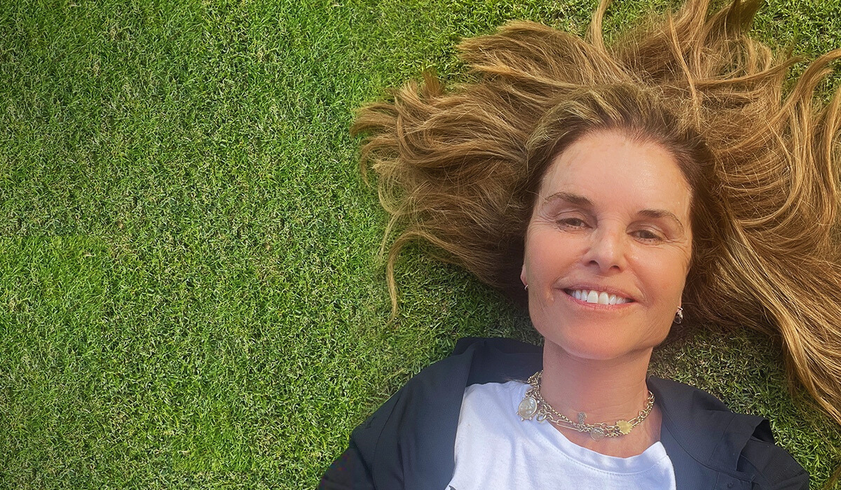 Selfie of Maria laying in grass, her shirt says 'Friend, Mother, Sister.'