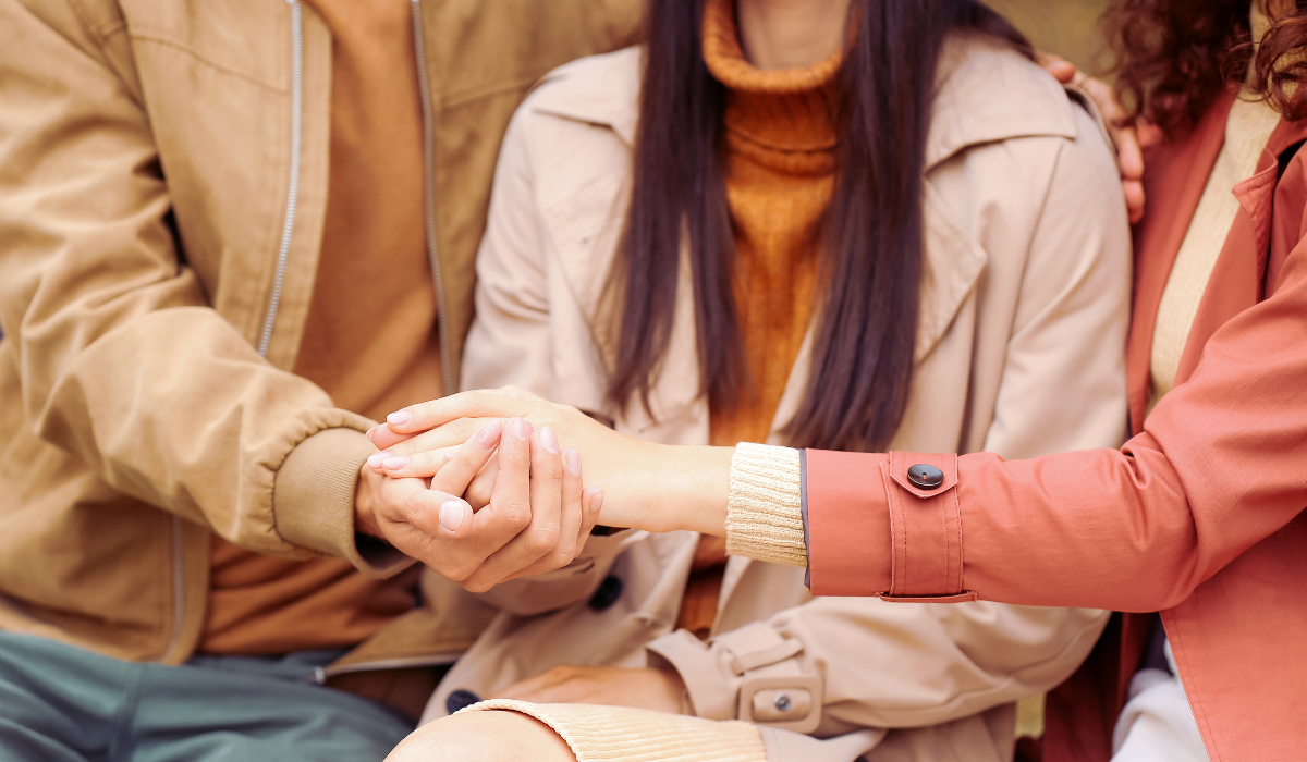 Two women and a man hold hands.