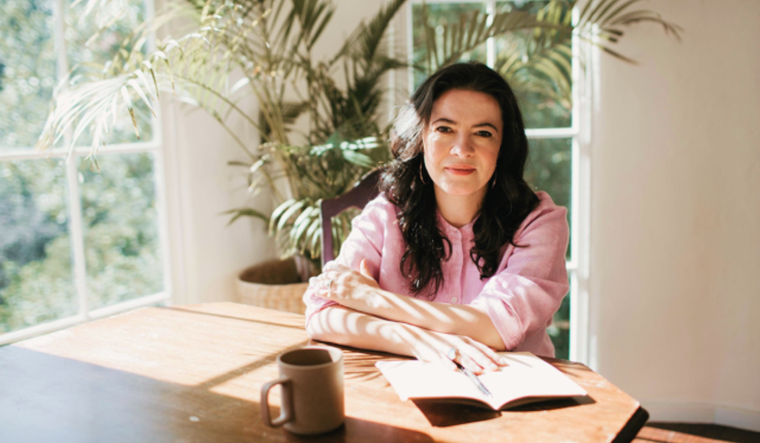 Tara Mohr at a table with a book, pen and a mug.