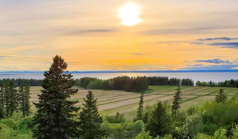 Sunset over green landscape with a lake.