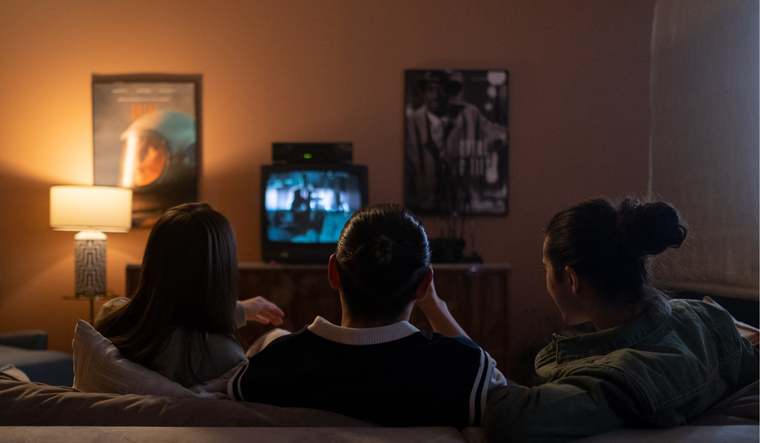 Three people watching TV in a living room.