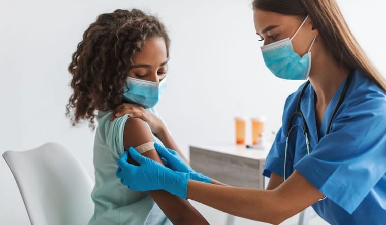 Kid getting a bandaid on arm after shot or vaccine. Credit: Canva.